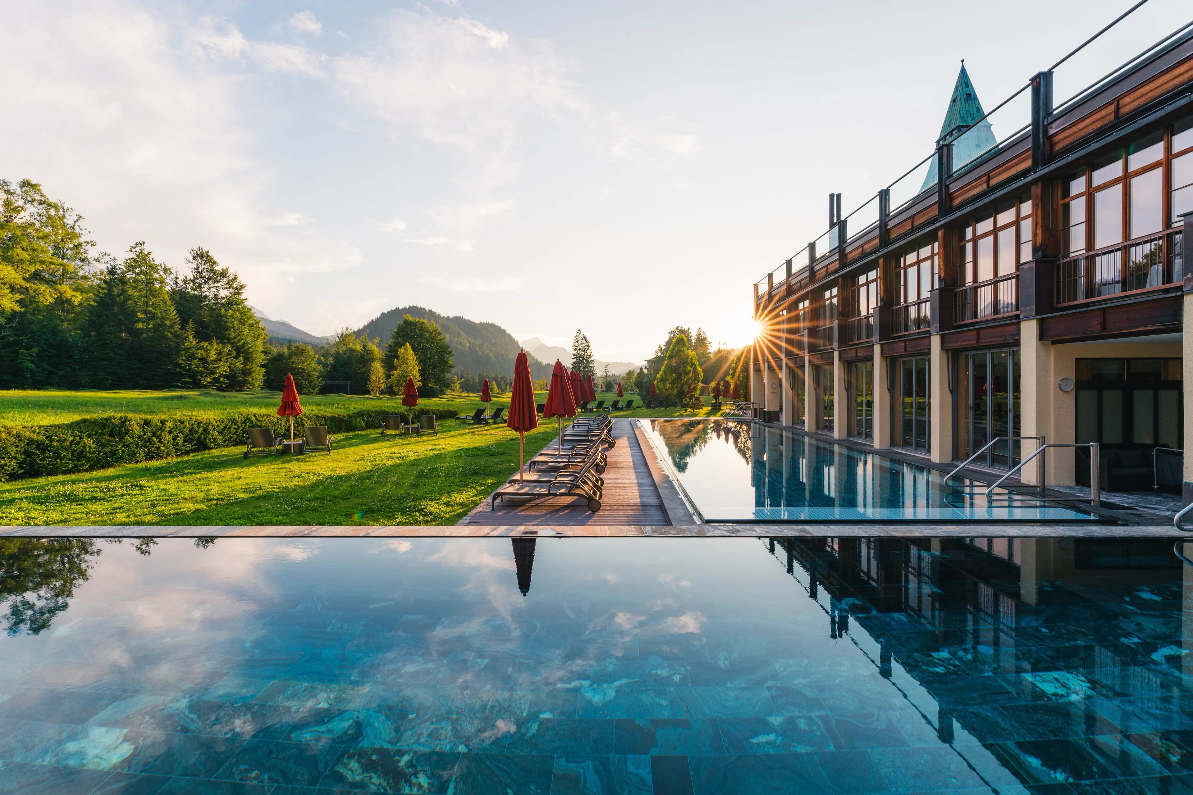 Badehaus mit Infinity-Pool im Sonnenuntergang vor dem Wettersteingebirge — Schloss Elmau (Foto: © Schloss Elmau)